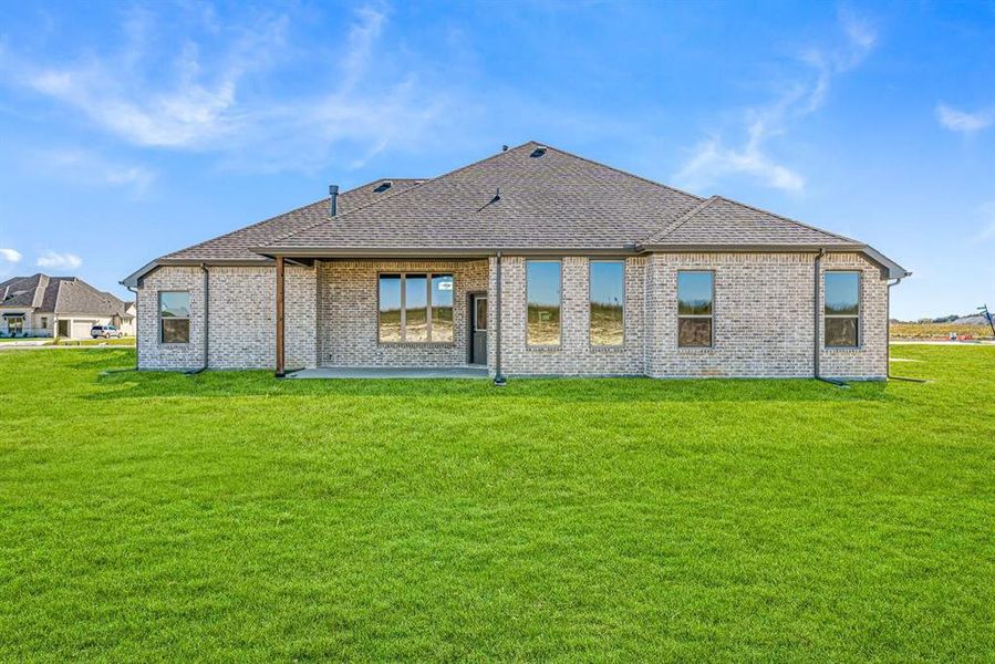 Rear view of house with a patio area, a yard, brick siding, and roof with shingles