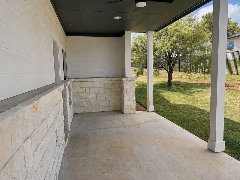An inviting covered patio provides a shaded retreat overlooking a well-maintained lawn.