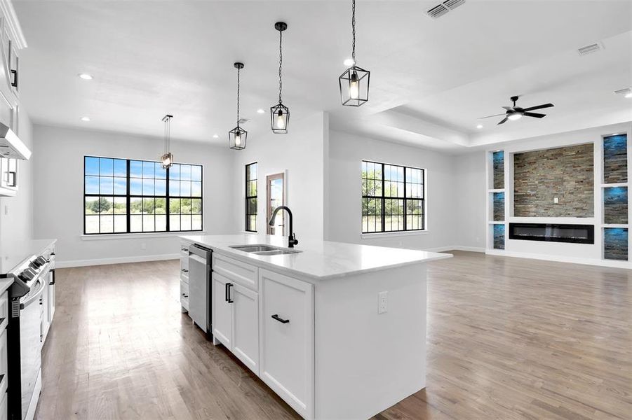 Kitchen with white cabinets, light wood-type flooring, and a center island with sink