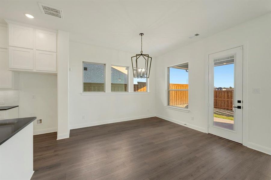 Unfurnished dining area with a chandelier and dark wood-style flooring Unfurnished dining area with a chandelier and dark wood-style flooring
