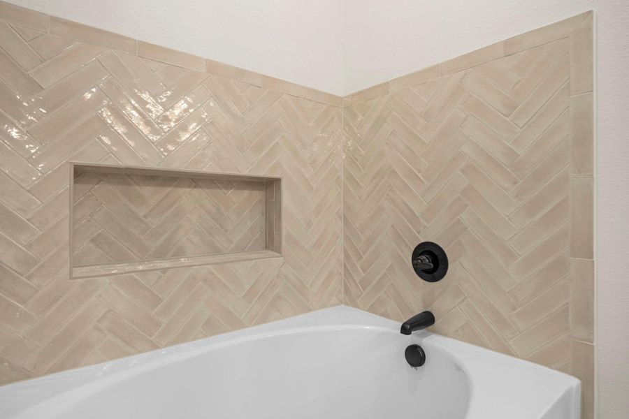 Herringbone tile detailing and a built-in niche elevate this modern bathing space.