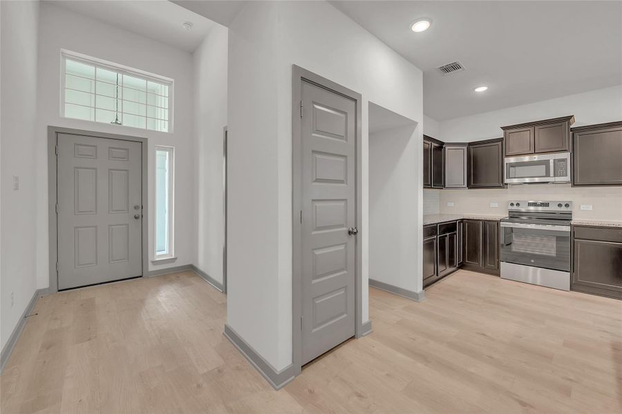 Kitchen with dark brown cabinetry, stainless steel appliances, light wood finished floors, and recessed lighting