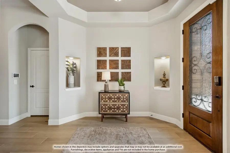 Foyer with tray ceiling, wood front door with iron glass insert, wall niches, and tile floors