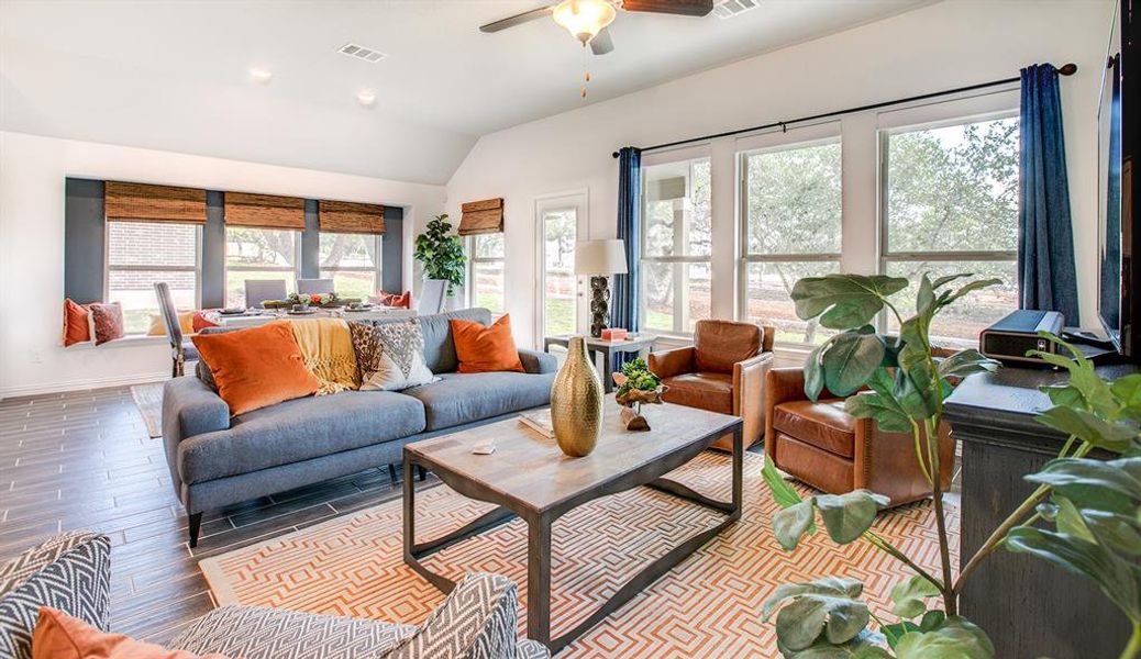Living room featuring wood finished floors, vaulted ceiling, and a ceiling fan Living room featuring wood finished floors, vaulted ceiling, and a ceiling fan