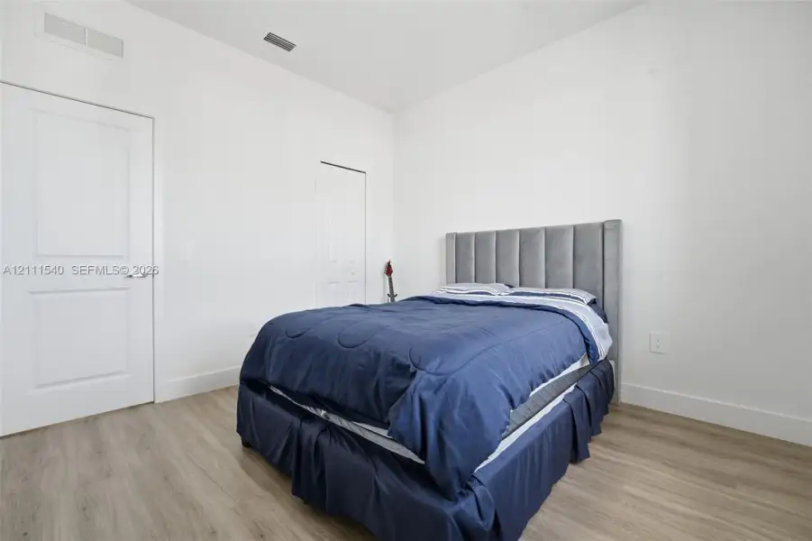 Neutral-toned interior featuring wood-finish flooring, crisp white walls, and multi-panel interior doors