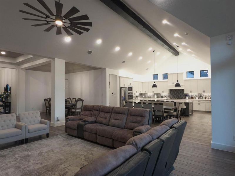 Living room with beam ceiling, dark wood-type flooring, high vaulted ceiling, and recessed lighting Living room with beam ceiling, dark wood-type flooring, high vaulted ceiling, and recessed lighting