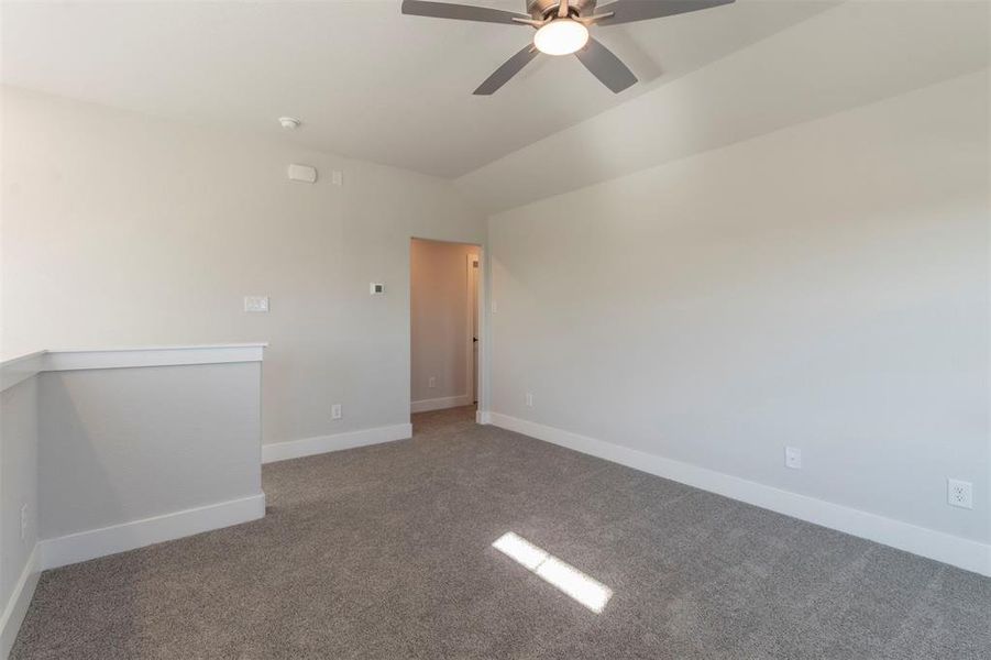 Carpeted spare room featuring ceiling fan and lofted ceiling