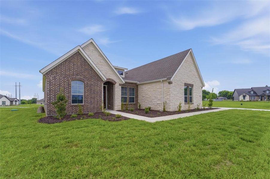The property features an exterior with a combination of brick and stone cladding, a dark-toned roof, and a well-maintained lawn