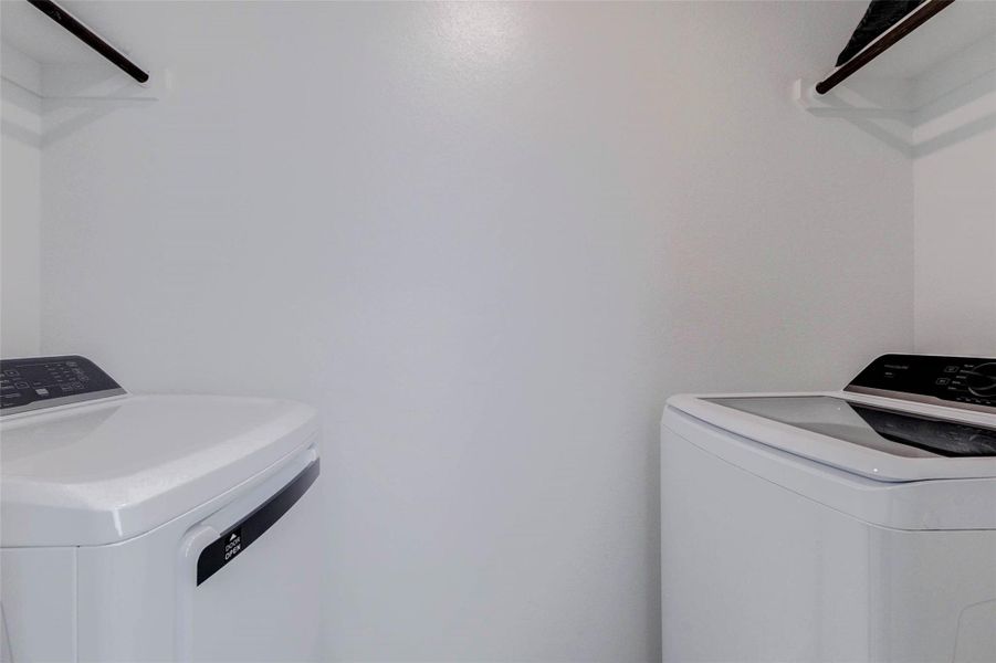 Dedicated laundry room with space for a full-size washer and dryer plus additional shelving for storage.