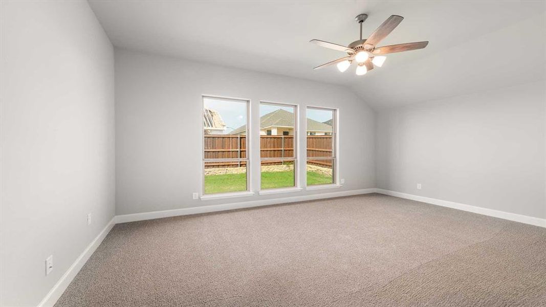 Carpeted empty room with vaulted ceiling and ceiling fan