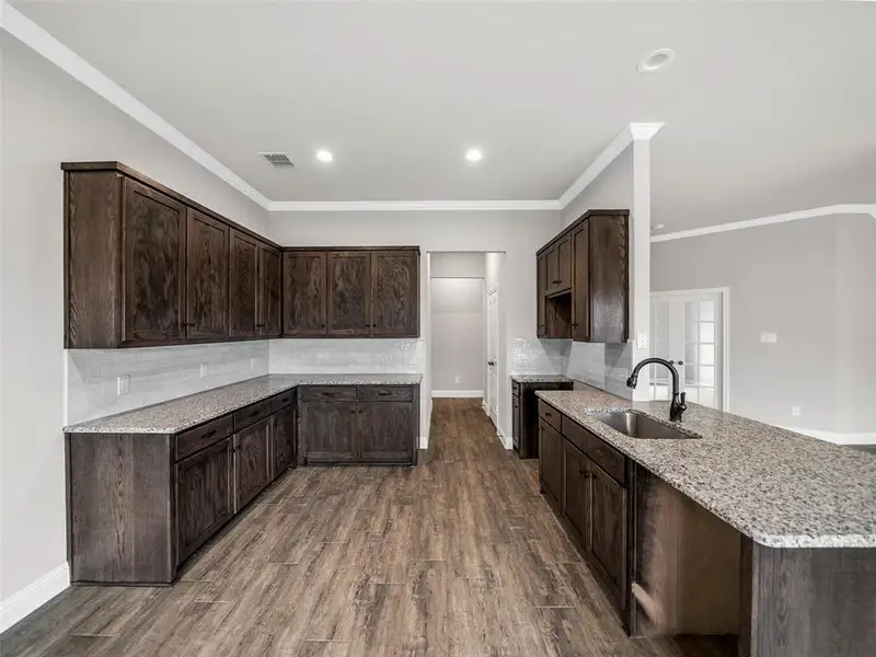 Kitchen with a sink, dark brown cabinets, tasteful backsplash, and light stone counters Kitchen with a sink, dark brown cabinets, tasteful backsplash, and light stone counters