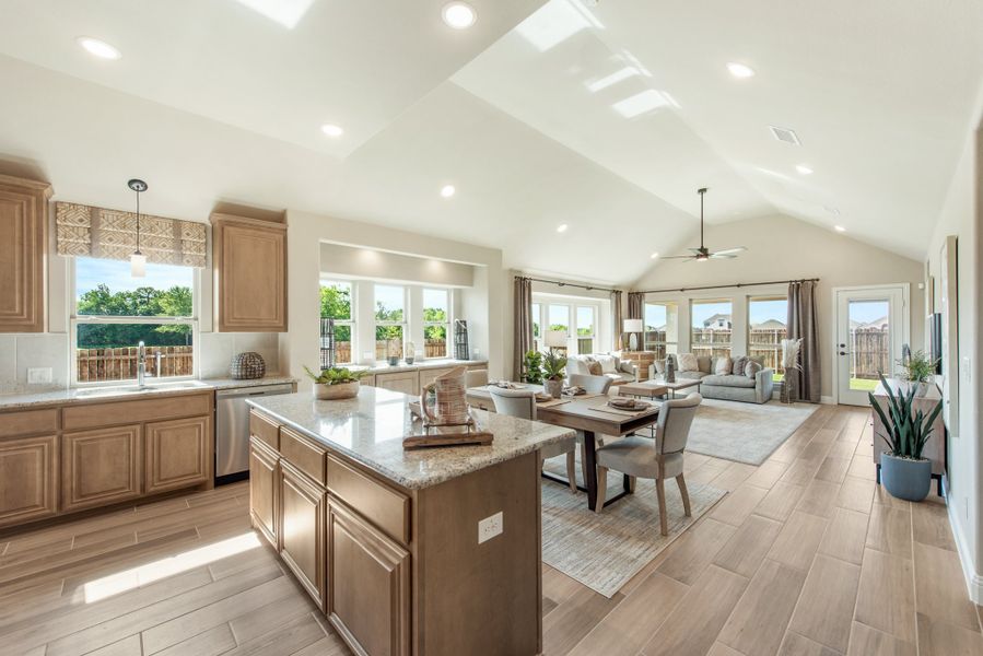 Open-concept kitchen and living area with granite island, vaulted ceiling, and wood-look tile floors
