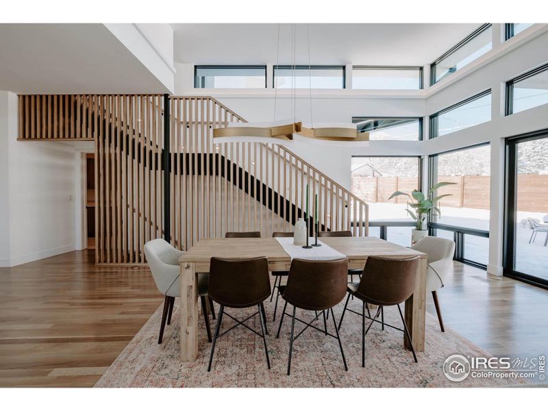 Modern but warm with this brass linear dining fixture and slat wood stair wall.