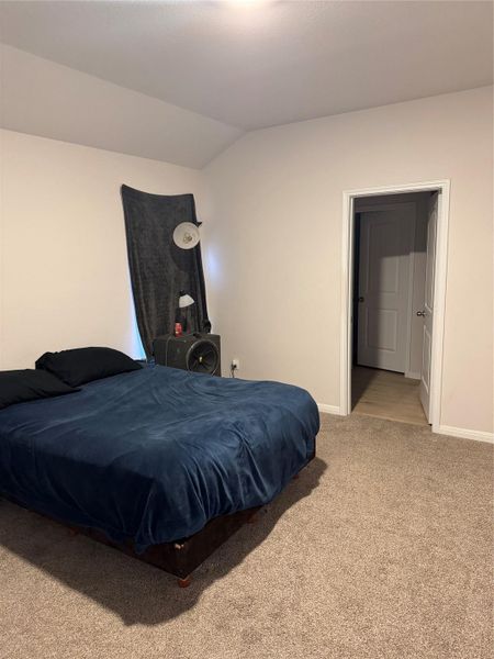 Bedroom featuring light carpet and vaulted ceiling