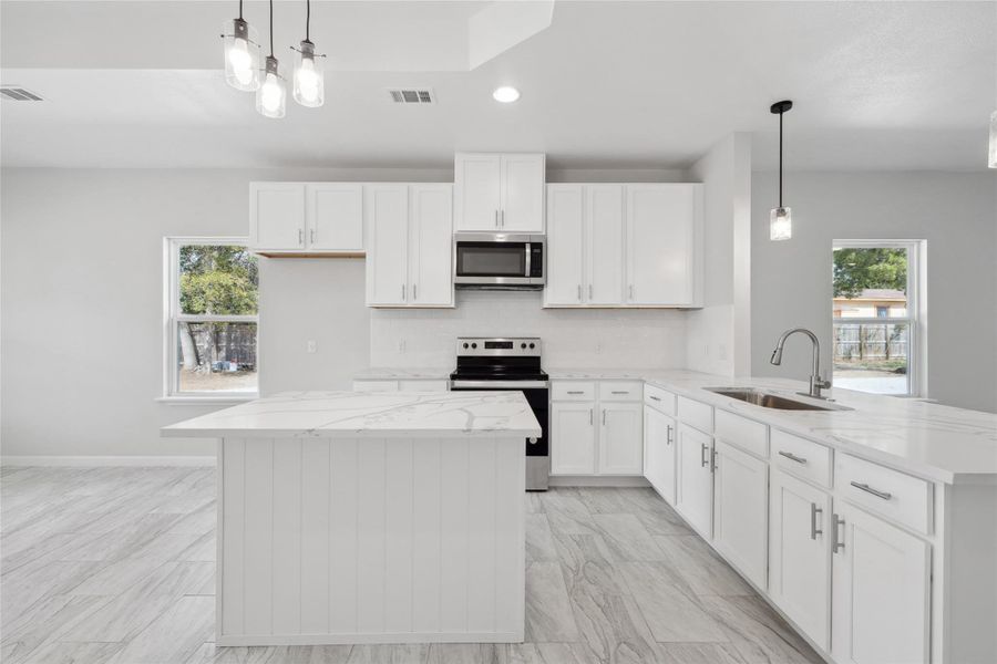 Kitchen with stainless steel appliances, a sink, a peninsula, white cabinets, and recessed lighting Kitchen with stainless steel appliances, a sink, a peninsula, white cabinets, and recessed lighting
