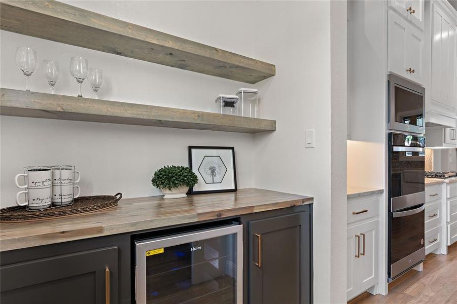 Bar featuring butcher block counters, light hardwood / wood-style floors, stainless steel appliances, white cabinets, and wine cooler