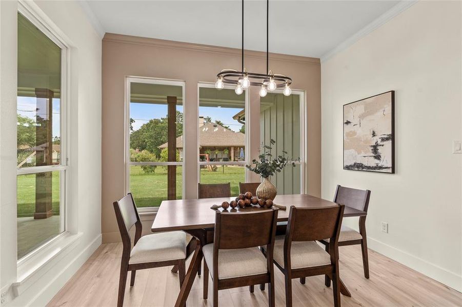 Dining room with light wood-type flooring, healthy amount of natural light, a chandelier, and ornamental molding Dining room with light wood-type flooring, healthy amount of natural light, a chandelier, and ornamental molding
