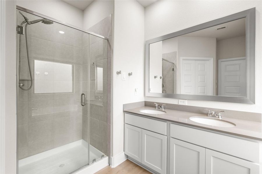 Dual vanities provide dedicated space for the morning routine, while the glass-enclosed shower offers a clean, modern design that enhances both form and function.