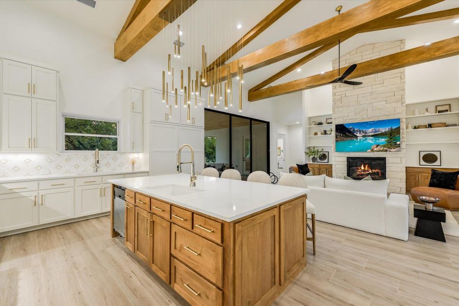 Dual tone kitchen with a center island with sink, a breakfast bar, open floor plan, a ceiling fan, and light wood finished floors