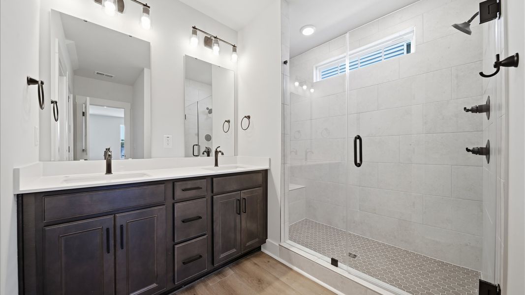 Notable primary bath featuring dual vanity, walk-in shower, and tasteful design touches throughout