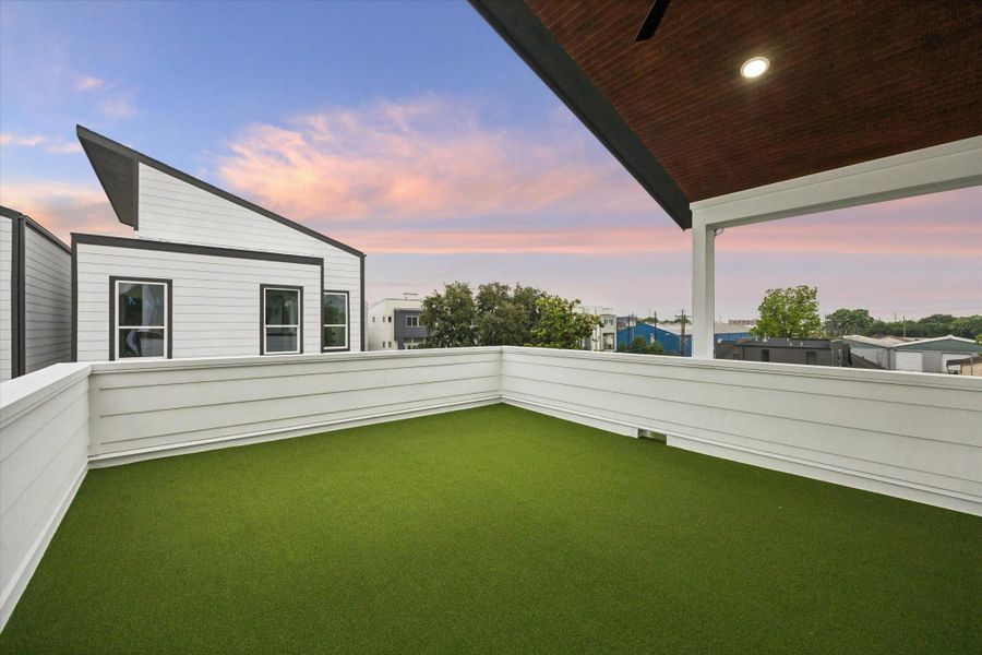 This photo showcases a modern rooftop terrace with artificial grass, surrounded by white fencing. It offers a spacious area for relaxation or entertaining, with a view of contemporary neighboring homes and a scenic sky. This photo showcases a modern rooftop terrace with artificial grass, surrounded by white fencing. It offers a spacious area for relaxation or entertaining, with a view of contemporary neighboring homes and a scenic sky.