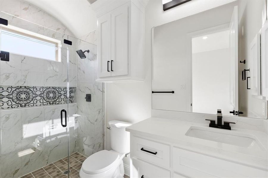 Bathroom featuring vanity, toilet, and a shower glass door