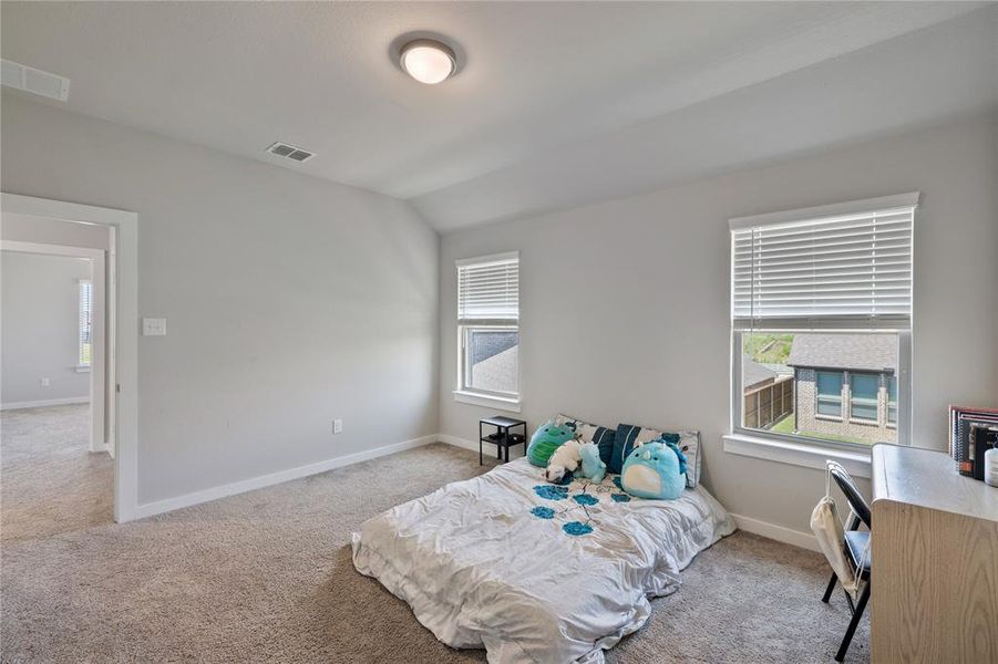 Bedroom with vaulted ceiling and light colored carpet