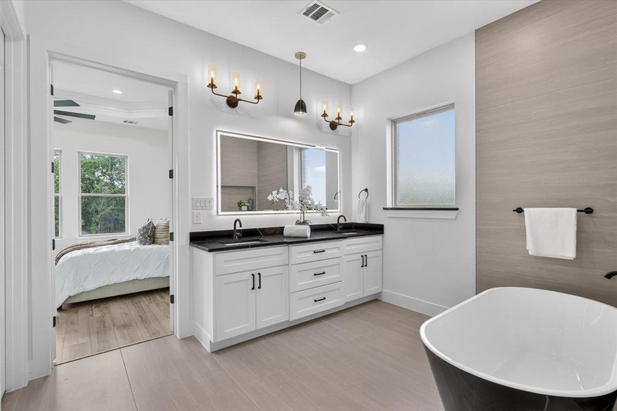 Ensuite bathroom featuring double vanity and a soaking tub