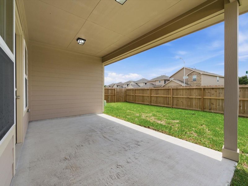The covered patio offers a comfortable outdoor retreat, perfect for morning coffee or evening gatherings.