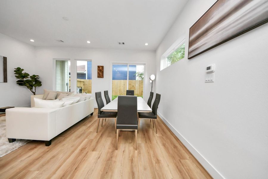 Discover a bright and modern dining area seamlessly connected to the living space, featuring sleek flooring, contemporary design, and abundant natural light for a perfect blend of style and comfort.