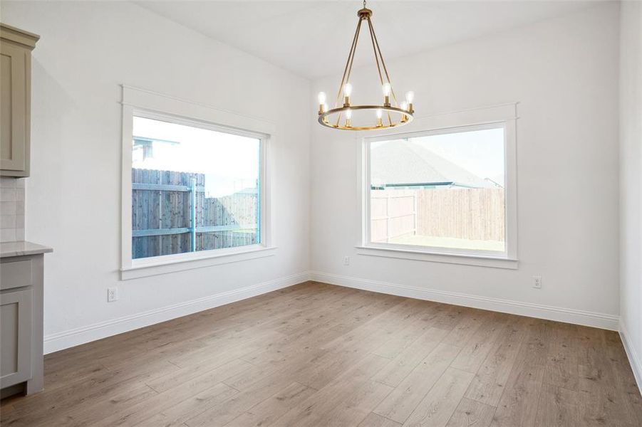 Unfurnished dining area featuring light hardwood / wood-style flooring and a notable chandelier