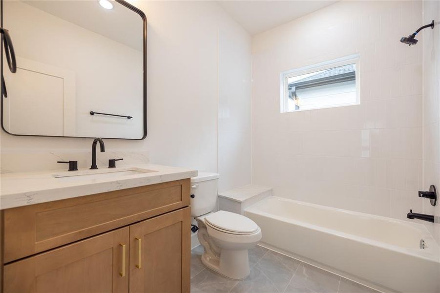 This stylish ensuite bath showcases elegant finishes throughout. A spacious vanity is lined with calacatta quartz with an under-mount sink and added storage is topped with gold hardware while the tub and shower combo is framed by classic white subway tiles, creating a clean and timeless look.