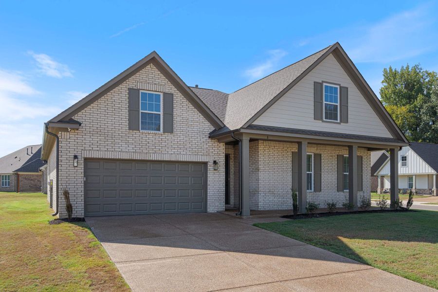 Light-colored brick exterior with gray siding accents, attached two-car garage, covered porch with columns, and a concrete driveway Light-colored brick exterior with gray siding accents, attached two-car garage, covered porch with columns, and a concrete driveway