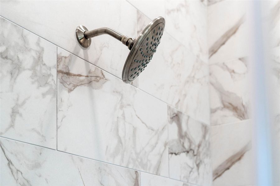 The large walk-in shower features a brushed nickel rain shower head on gorgeous marble tile.