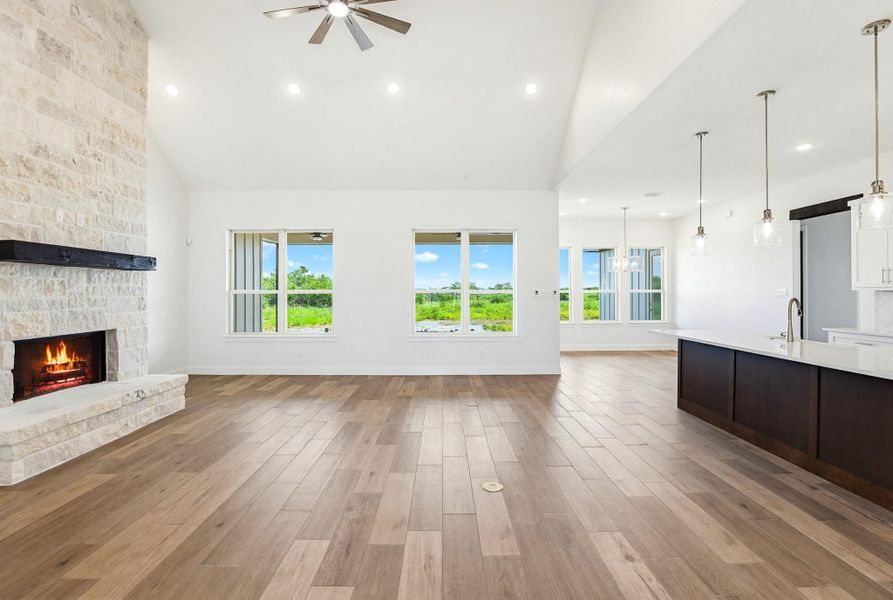 A spacious living area features a grand stone fireplace, vaulted ceilings, and views of the surrounding natural landscape.