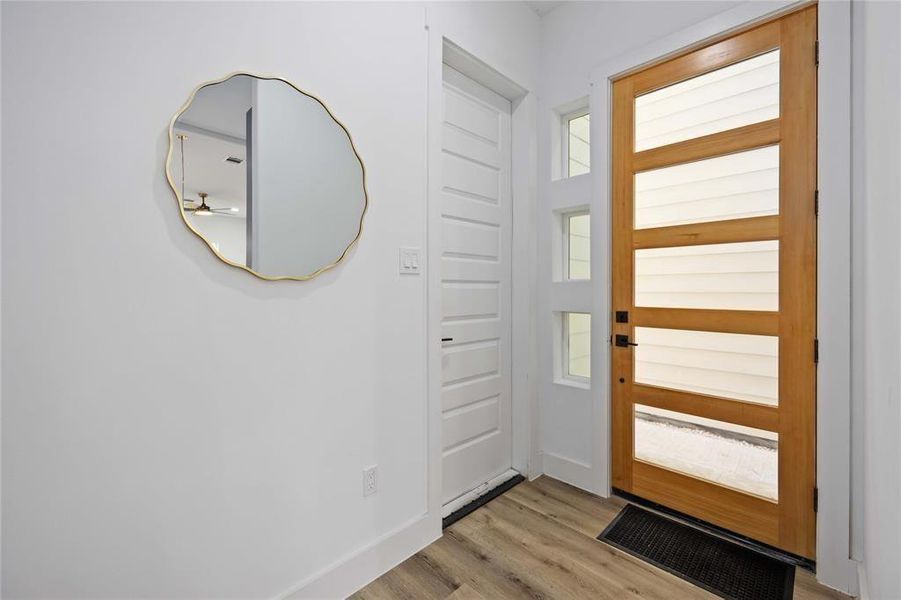 The entry way includes a modern door with glass inserts that allow plenty of light into the home. The door to the left leads to a two car garage.