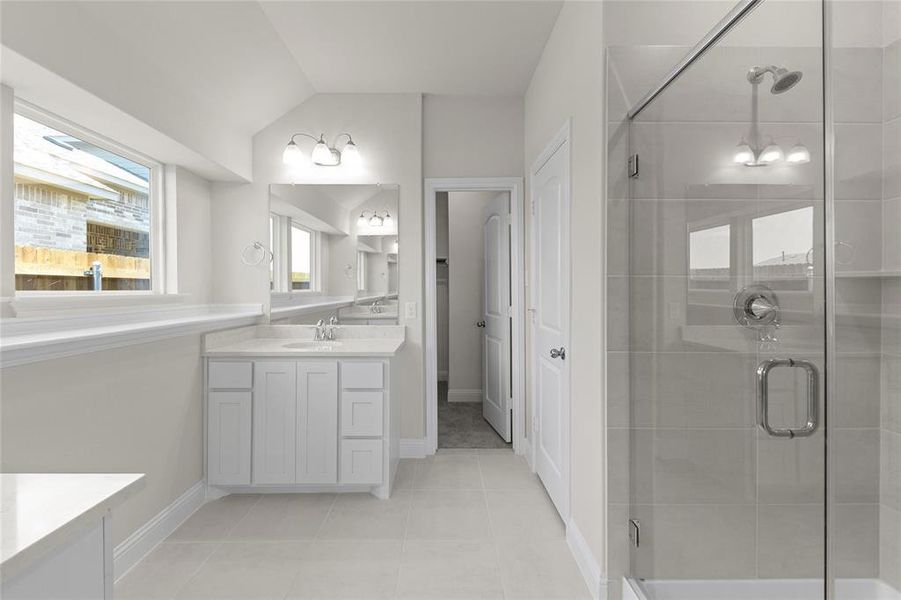 Bathroom featuring tile flooring, vanity, a shower with door, and lofted ceiling