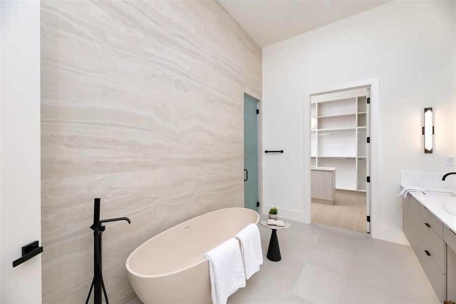 Full bathroom featuring vanity, a spacious closet, a freestanding tub, and a shower stall
