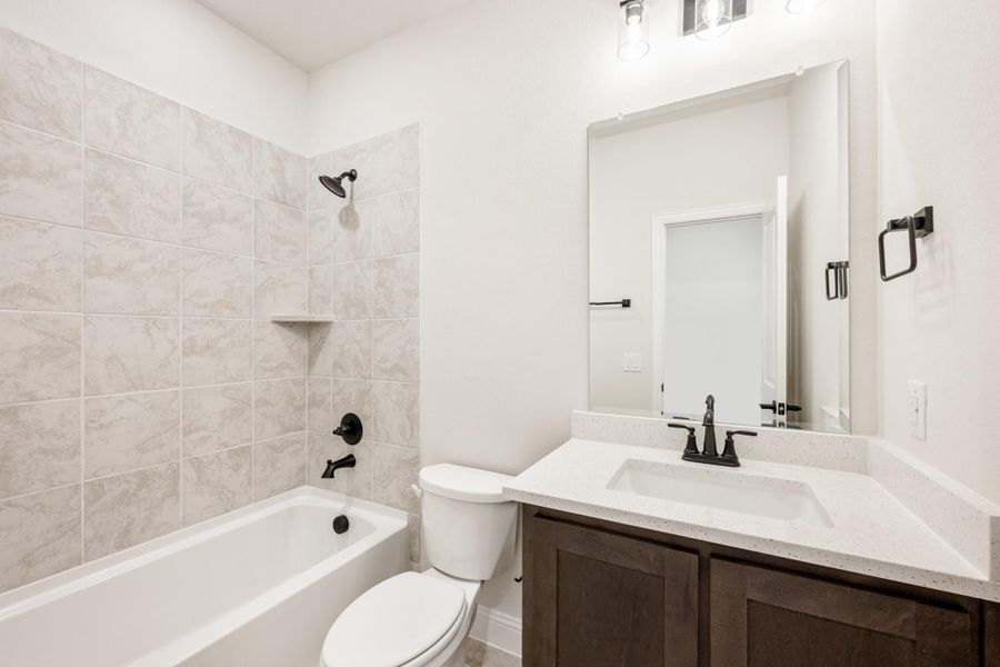 Bathroom with tiled tub-shower combo, dark wood vanity, white quartz countertop, and matte black fixtures