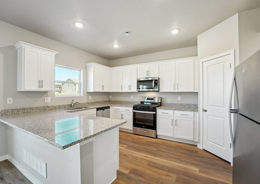 The kitchen has stainless steel appliances and plank flooring.