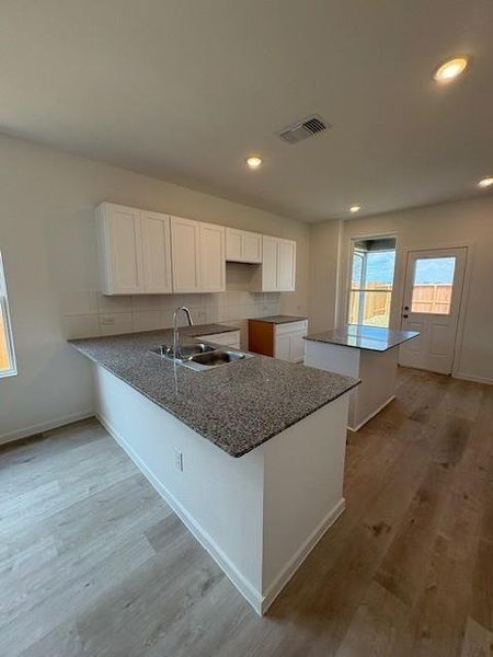 Island kitchen has granite countertops and a ceramic tile backsplash. Island kitchen has granite countertops and a ceramic tile backsplash.