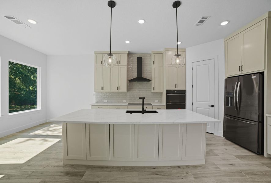 Kitchen with black appliances, light stone counters, decorative backsplash, light wood-type flooring, and recessed lighting Kitchen with black appliances, light stone counters, decorative backsplash, light wood-type flooring, and recessed lighting