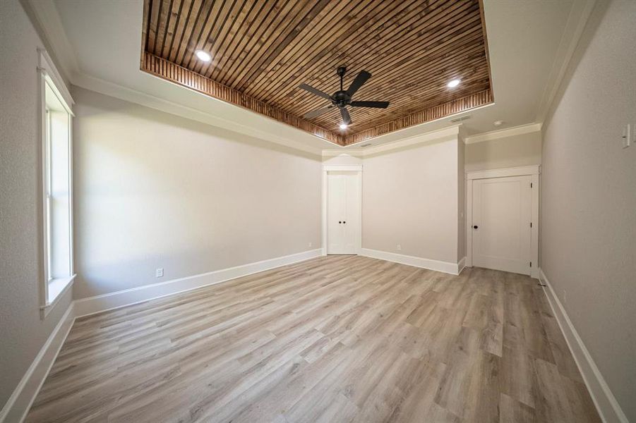 Unfurnished room featuring wooden ceiling, a tray ceiling, light wood finished floors, ornamental molding, and a ceiling fan Unfurnished room featuring wooden ceiling, a tray ceiling, light wood finished floors, ornamental molding, and a ceiling fan
