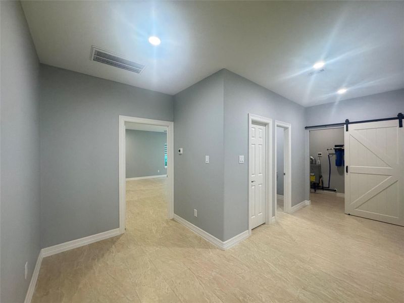 Hallway leading to primary bedroom on left, powder room and utility room to the right