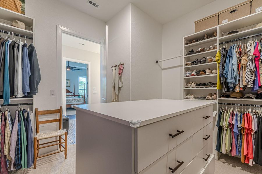 Walk in closet with light carpet and ceiling fan