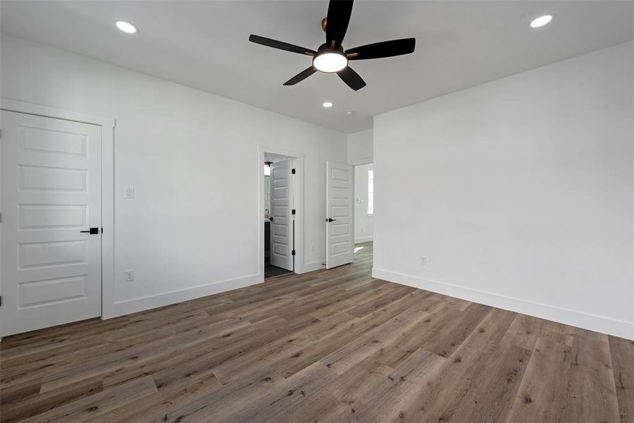 Another view of this bedroom with recessed lights and a ceiling fan.