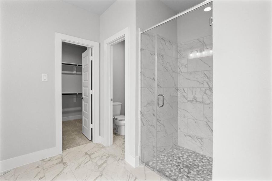 This additional view of the primary bath showcased the large walk-in shower with tile surround, privacy toilet area, and spacious walk-in closet.