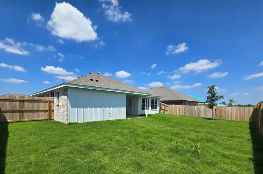 A neatly manicured lawn extends from the back of the house, offering a private outdoor retreat.