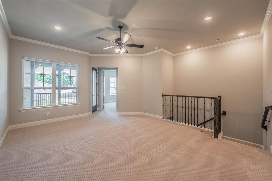Spacious carpeted room featuring a ceiling fan, recessed lighting, and crown molding