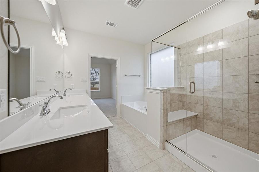 Bathroom featuring a stall shower, a garden tub, and double vanity